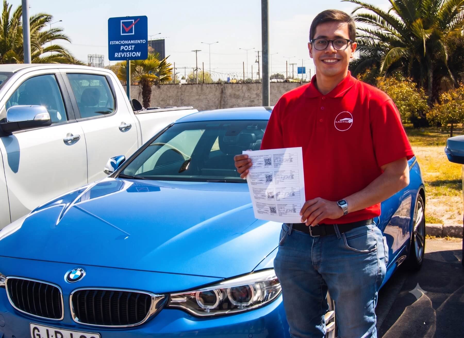 Cliente con su certificado de revisión técnica aprobada junto a su auto en la planta PRT